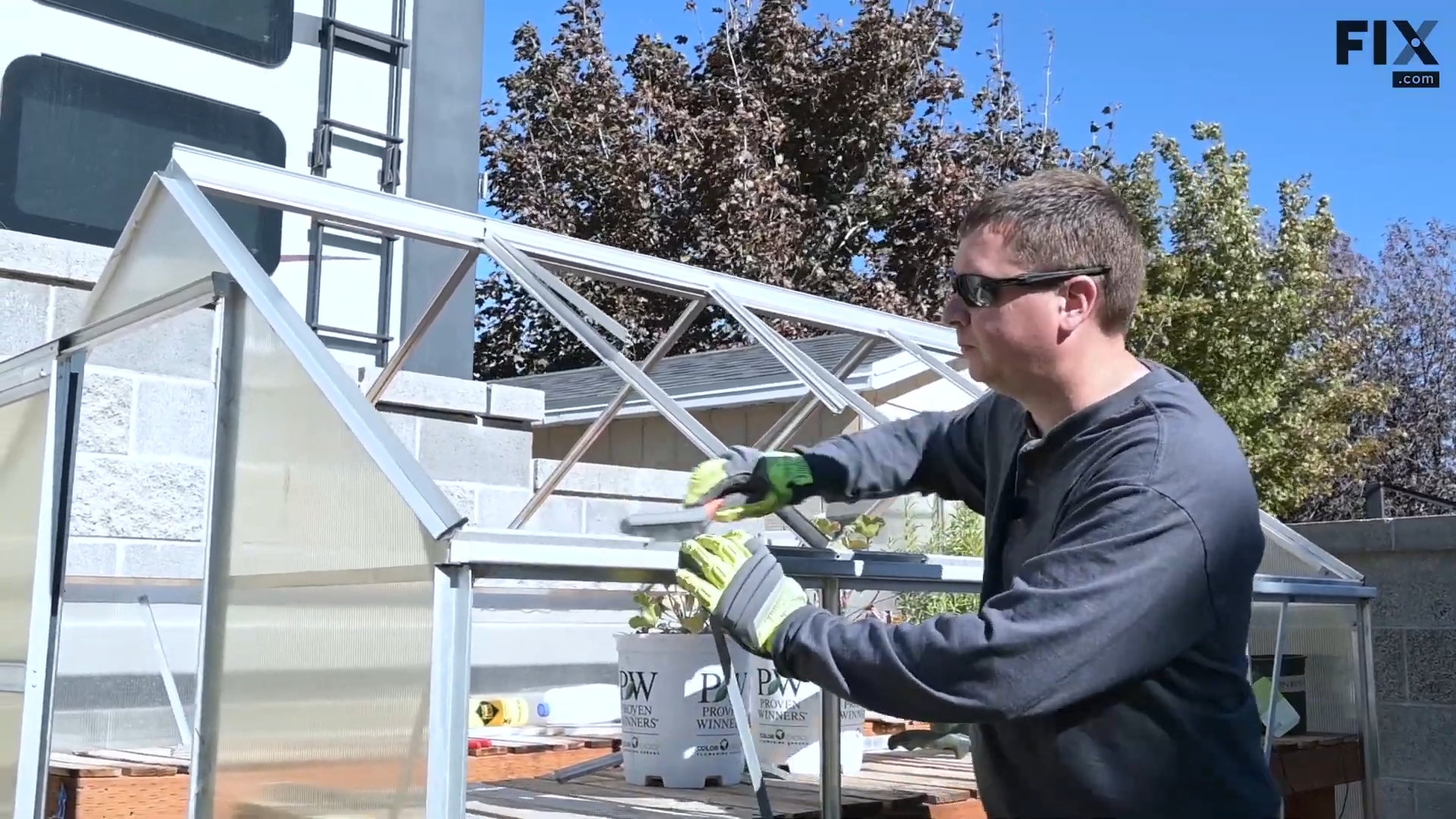 Expert technician cleaning the frame of a greenhouse with a wire brush.