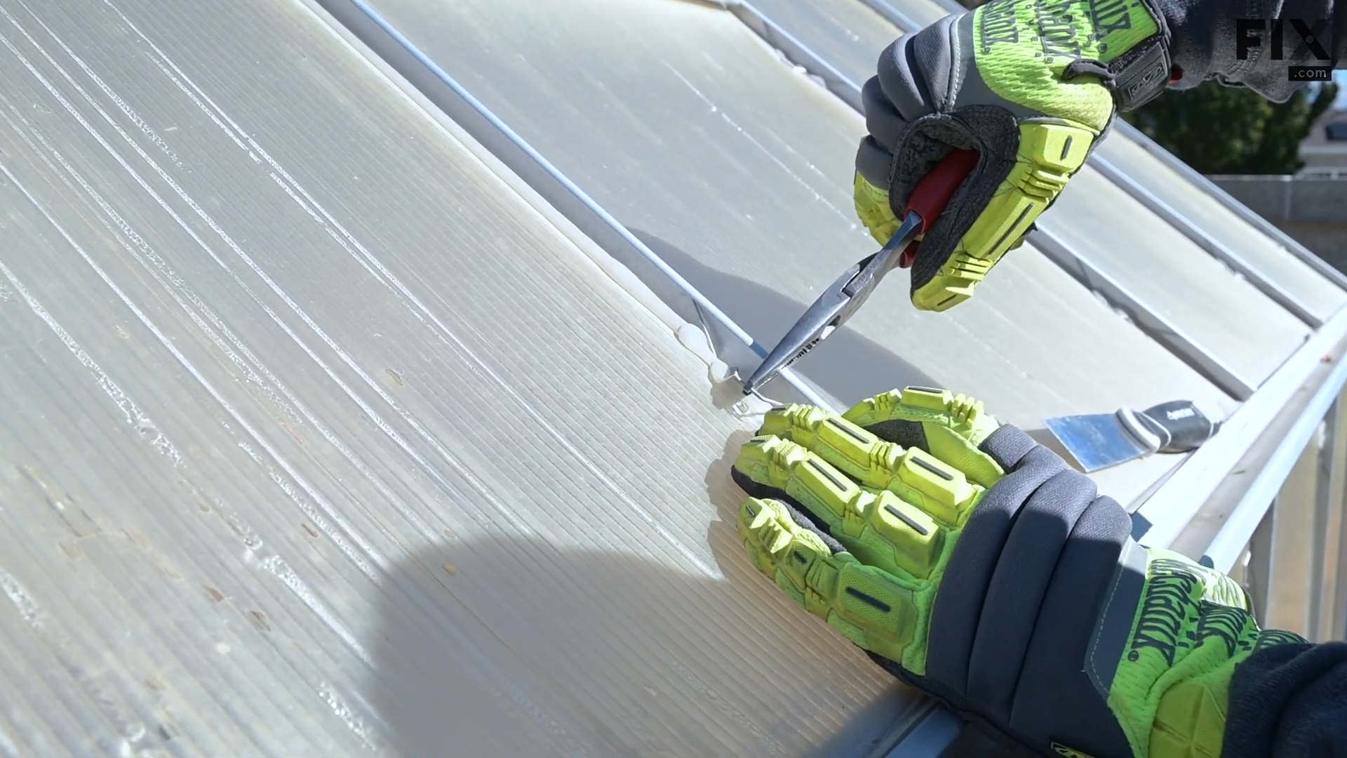 Expert technician removing the steel fixing clips from a roof panel of a greenhouse using pliers and wearing gloves