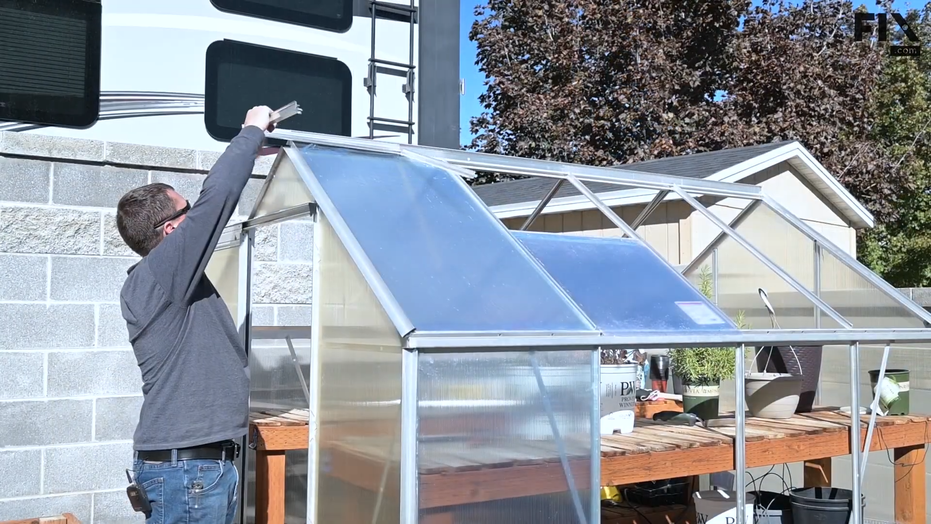 Expert technician removing the vent's frame from a greenhouse by pulling it out of the roof with their hands